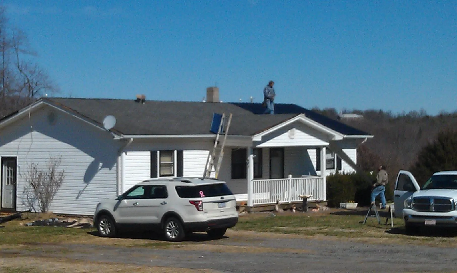 Roofers stripping shingles from a white ranch house roof in Morgantown
